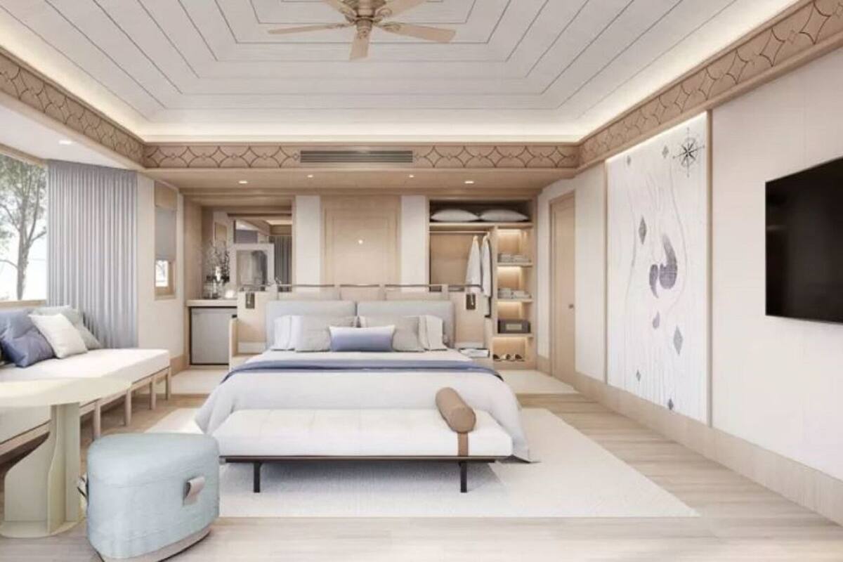 A bedroom with a bed, bedside table, seating area, and a TV.