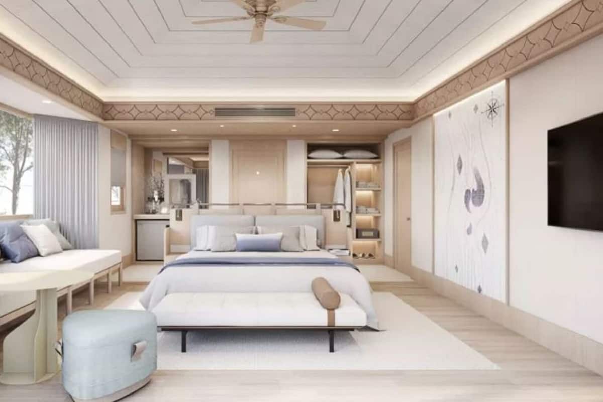 A bedroom with a bed, bedside table, seating area, and a TV.