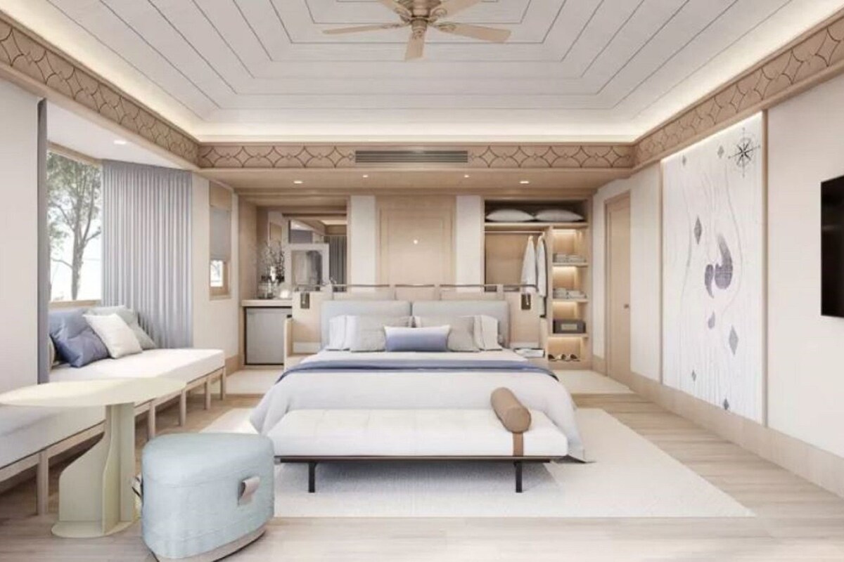 Un dormitorio con cama, mesita de noche, zona de estar y televisión.