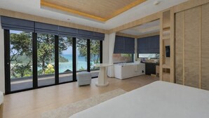 Un dormitorio moderno con una cama grande, un escritorio y vistas al océano.