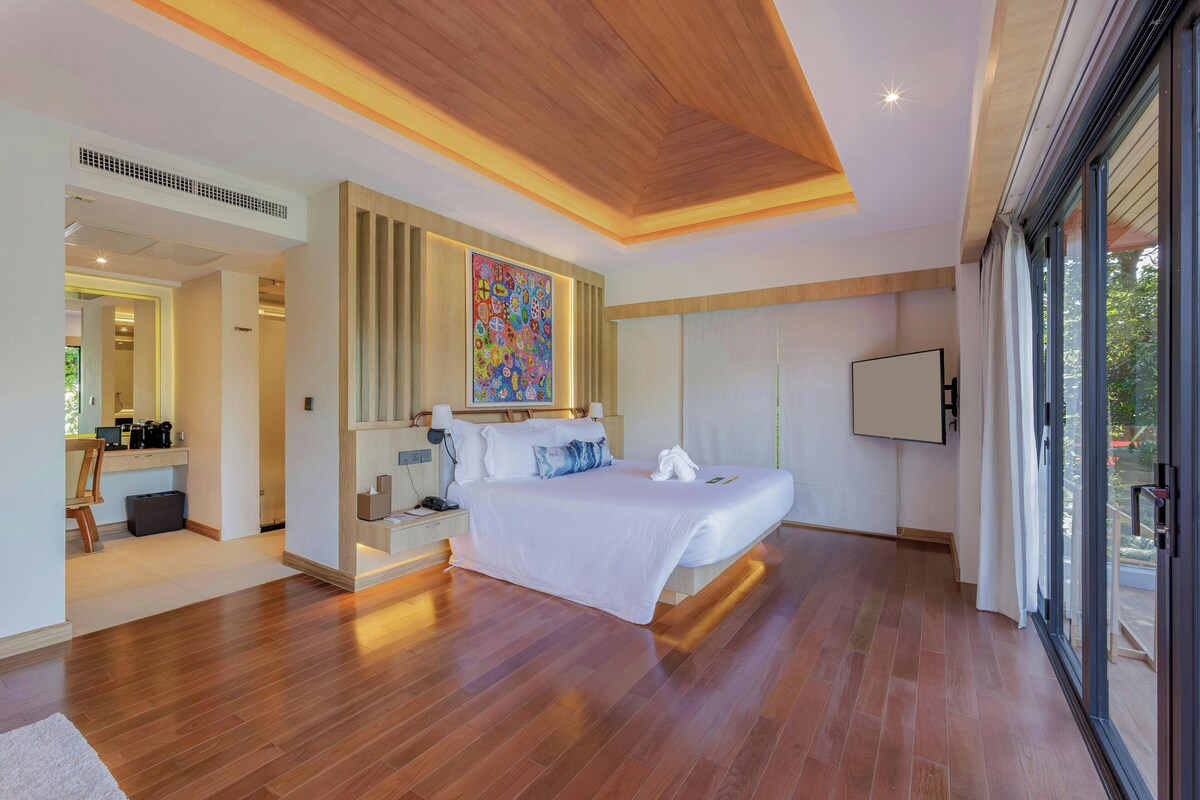 A modern bedroom with a large bed, a desk, and a painting on the wall.