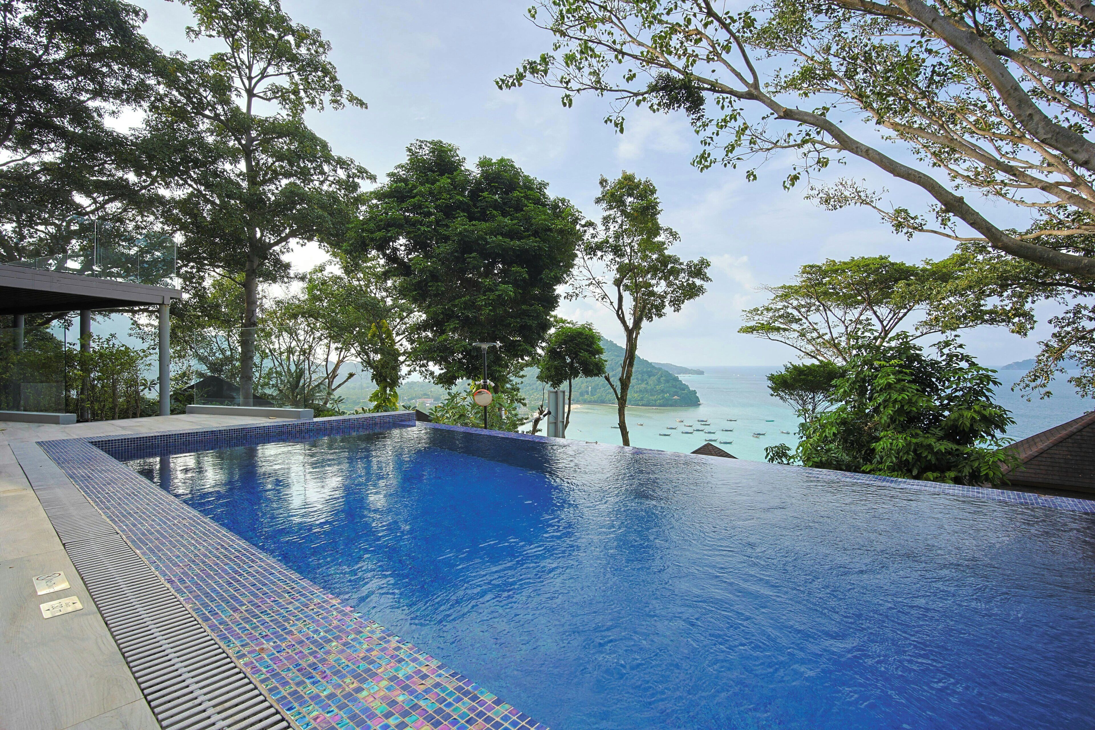 A swimming pool with a view of the sea, surrounded by trees.