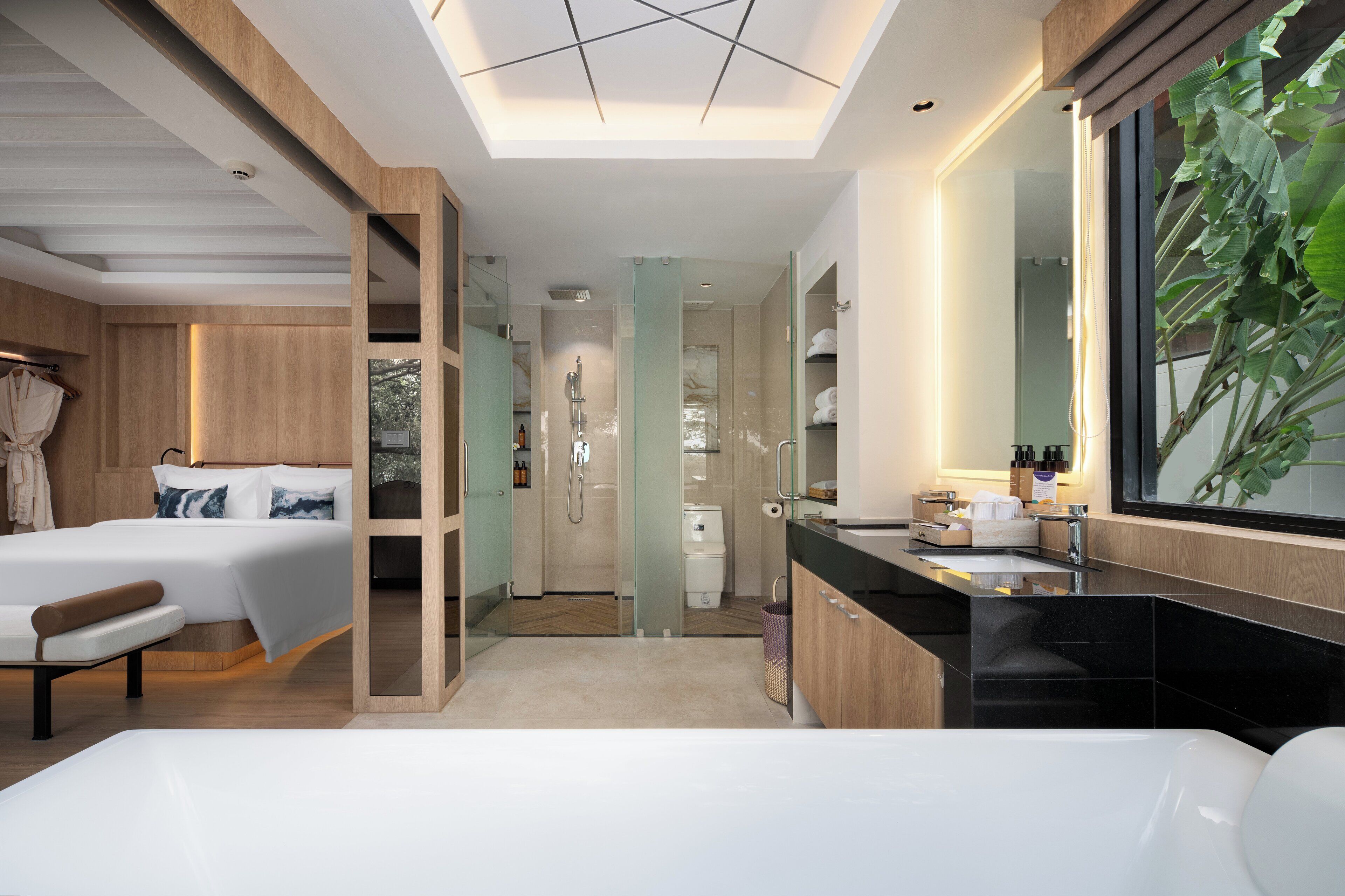 A modern hotel room with a large bed, a separate bathroom, and a large window with a view.