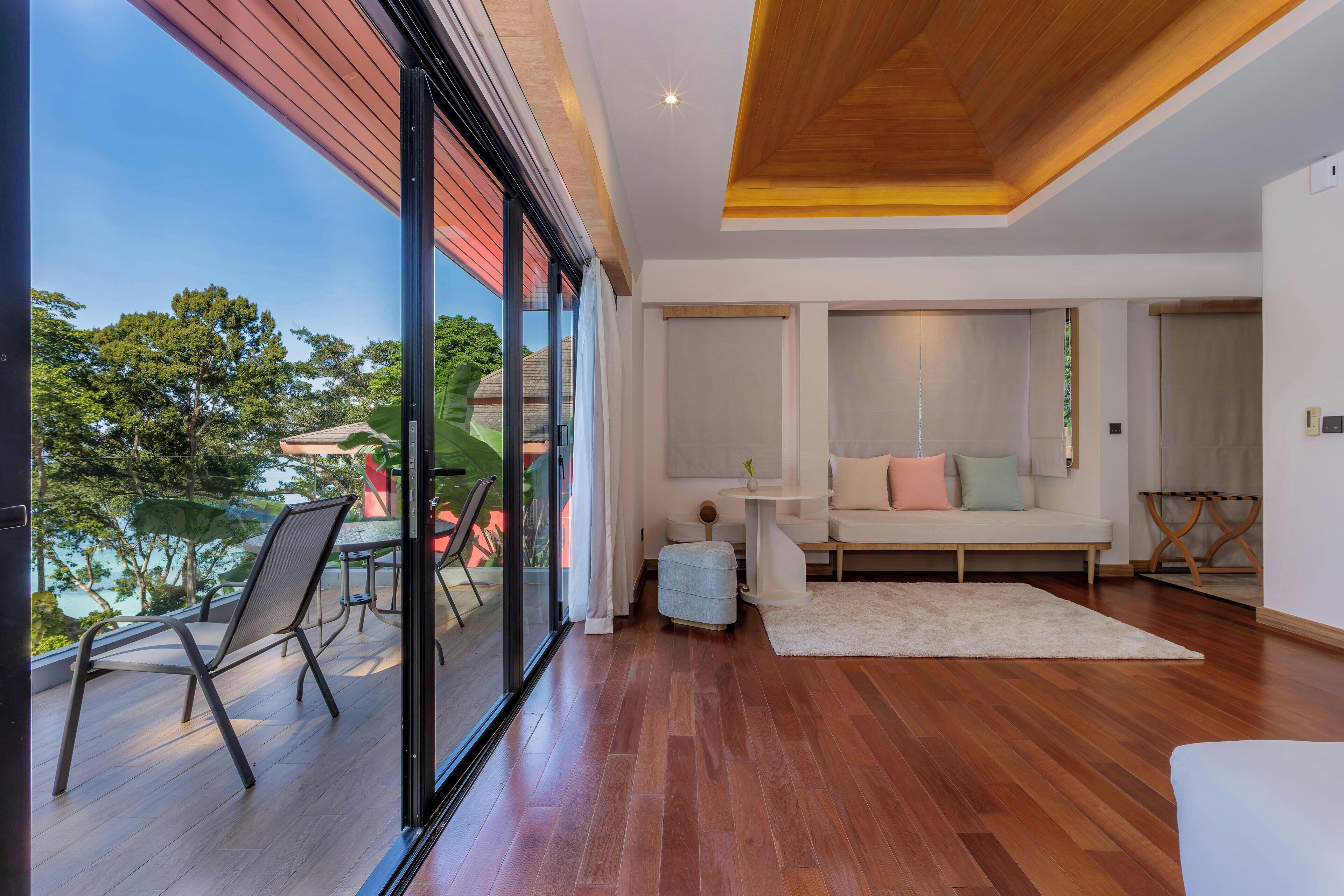 A modern interior with a wooden ceiling, large windows, a sofa, and a dining area.