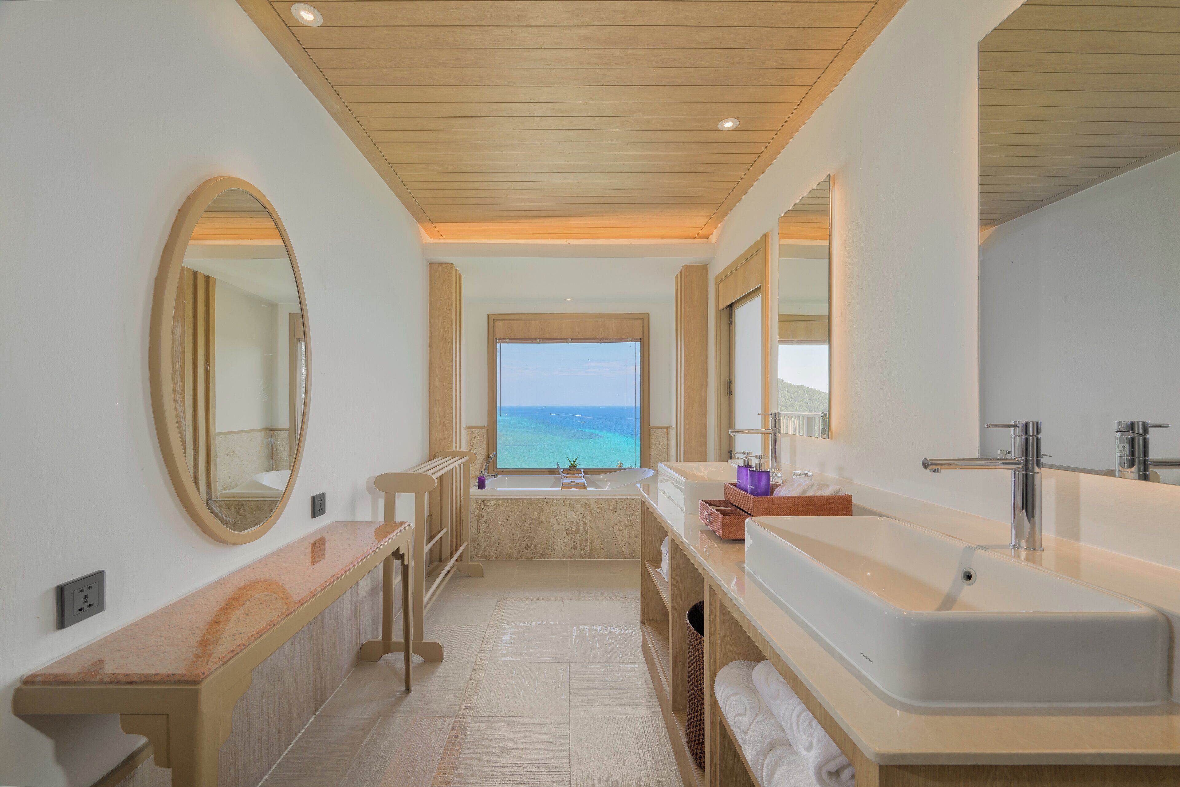 A modern bathroom with a large bathtub, a double sink, and a large mirror.