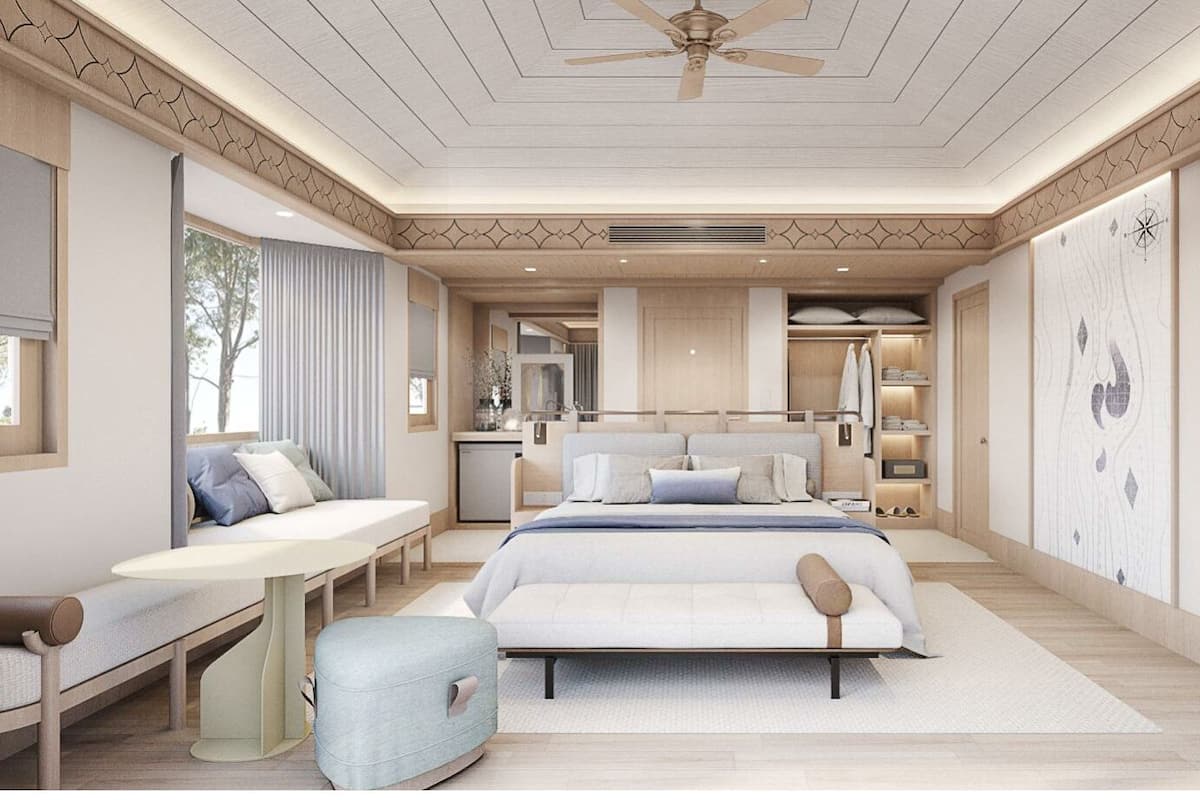 A modern bedroom with a large bed, bedside tables, a seating area, and a TV.