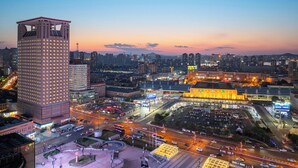 A cityscape at dusk with illuminated buildings and a prominent tower. - Dalian Youxi-ChengYuan Hotel (Dalian)
