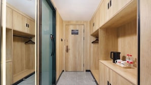 A hotel corridor with wooden lockers, a glass door, and a small table with a coffee maker and water bottles. - Dalian Youxi-ChengYuan Hotel (Dalian)