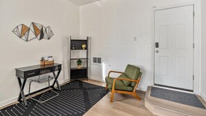 A modern room with a black and white striped rug, a desk with a chair, a green armchair, a black shelving unit, and a white door. - 4BD/3BA MTN Views/HTUB Close to Ski Resorts (Cottonwood Heights)