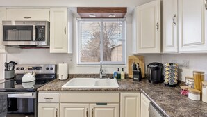 A kitchen with white cabinets, a granite countertop, a stainless steel microwave, a stove, and a sink. - 4BD/3BA MTN Views/HTUB Close to Ski Resorts (Cottonwood Heights)
