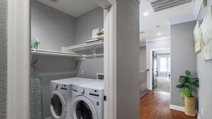 A laundry area with two front-loading washing machines, a drying rack, and a radiator.