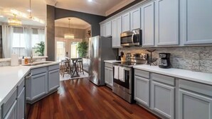A modern kitchen with white cabinets, stainless steel appliances, and a marble backsplash.