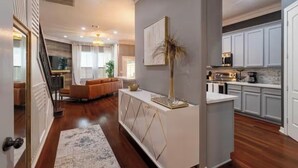 A modern kitchen with white cabinets, a central island, and a dining area with a sofa and coffee table.