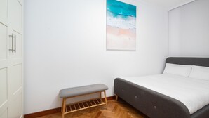 A bedroom with a bed, a bench, and a wall-mounted painting.