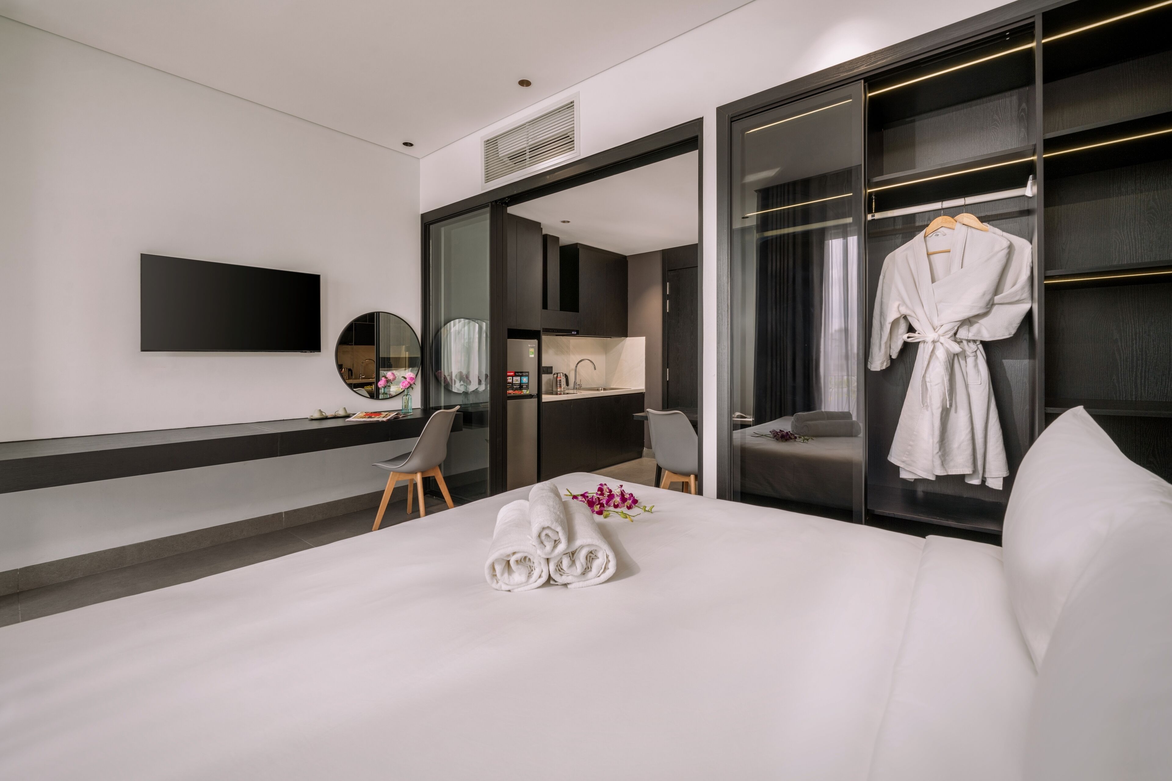 Une chambre d’hôtel moderne dotée d’un grand lit, d’un bureau, d’une chaise, d’une télévision et d’un dressing.
