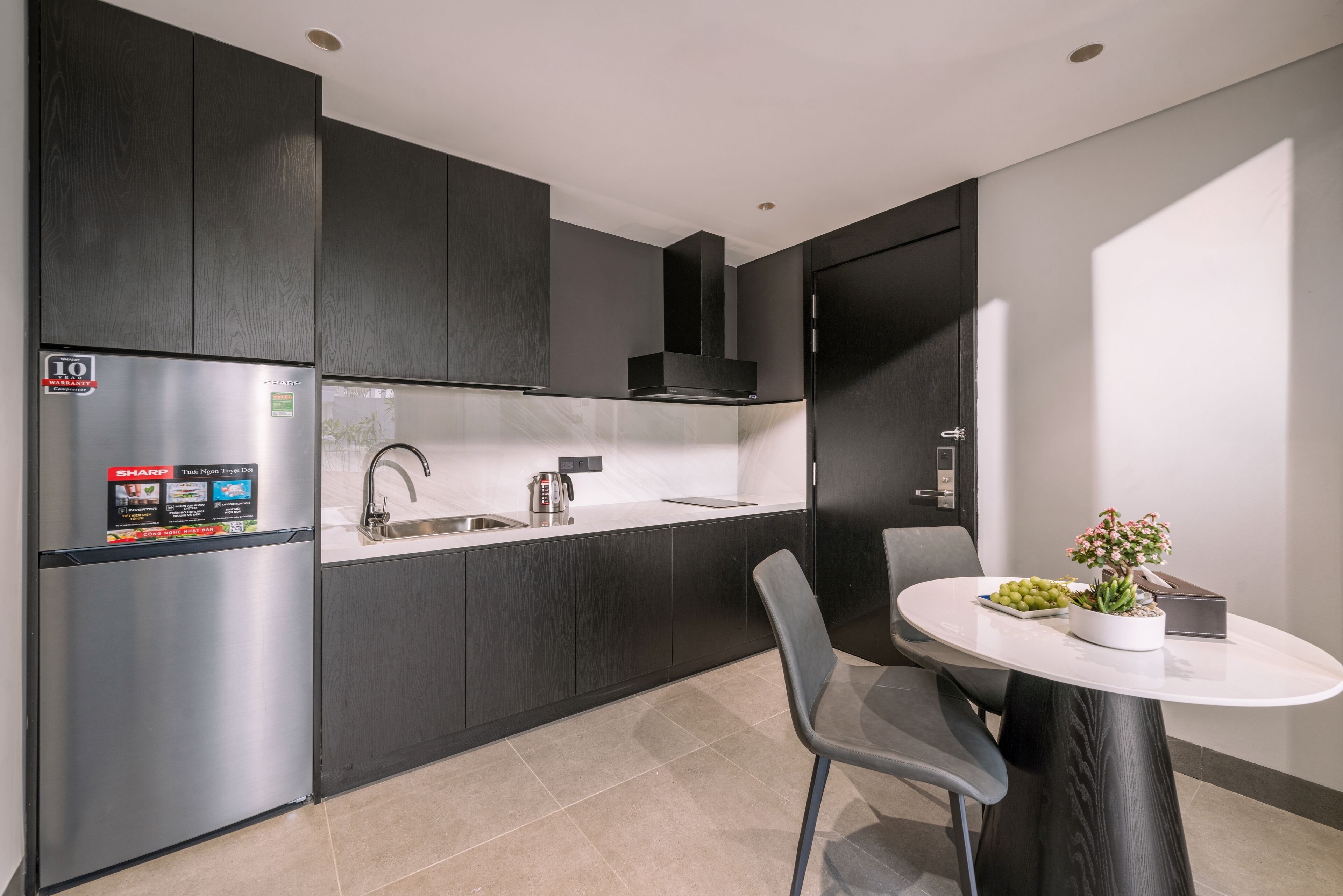 A modern kitchen with a built-in refrigerator, a sink, and a dining area with a table and chairs.