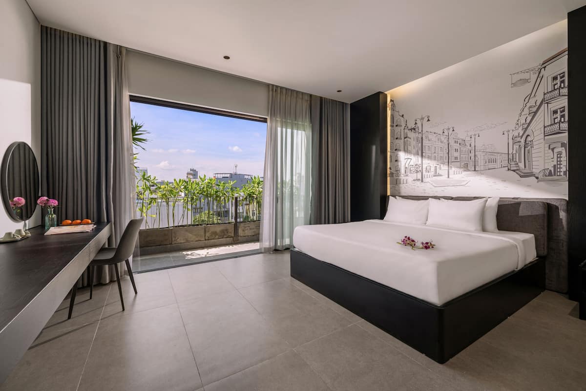 A modern hotel room with a large bed, a desk, and a view of the city.
