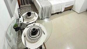 A hotel room with a bed, a dining table with two plates, and a TV mounted on the wall.