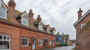 A quiet street lined with traditional brick houses, each with distinct pitched roofs and multiple chimneys. - Castle Cottage, Orford (Orford)
