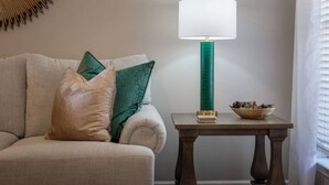 A beige sofa with two pillows, a green lamp on a wooden table, and a bowl of pinecones. - Large Home in Hoover minutes from the MET! (Birmingham)