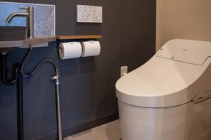 Un baño moderno con lavamanos empotrado, inodoro y dispensador de toallas de papel.