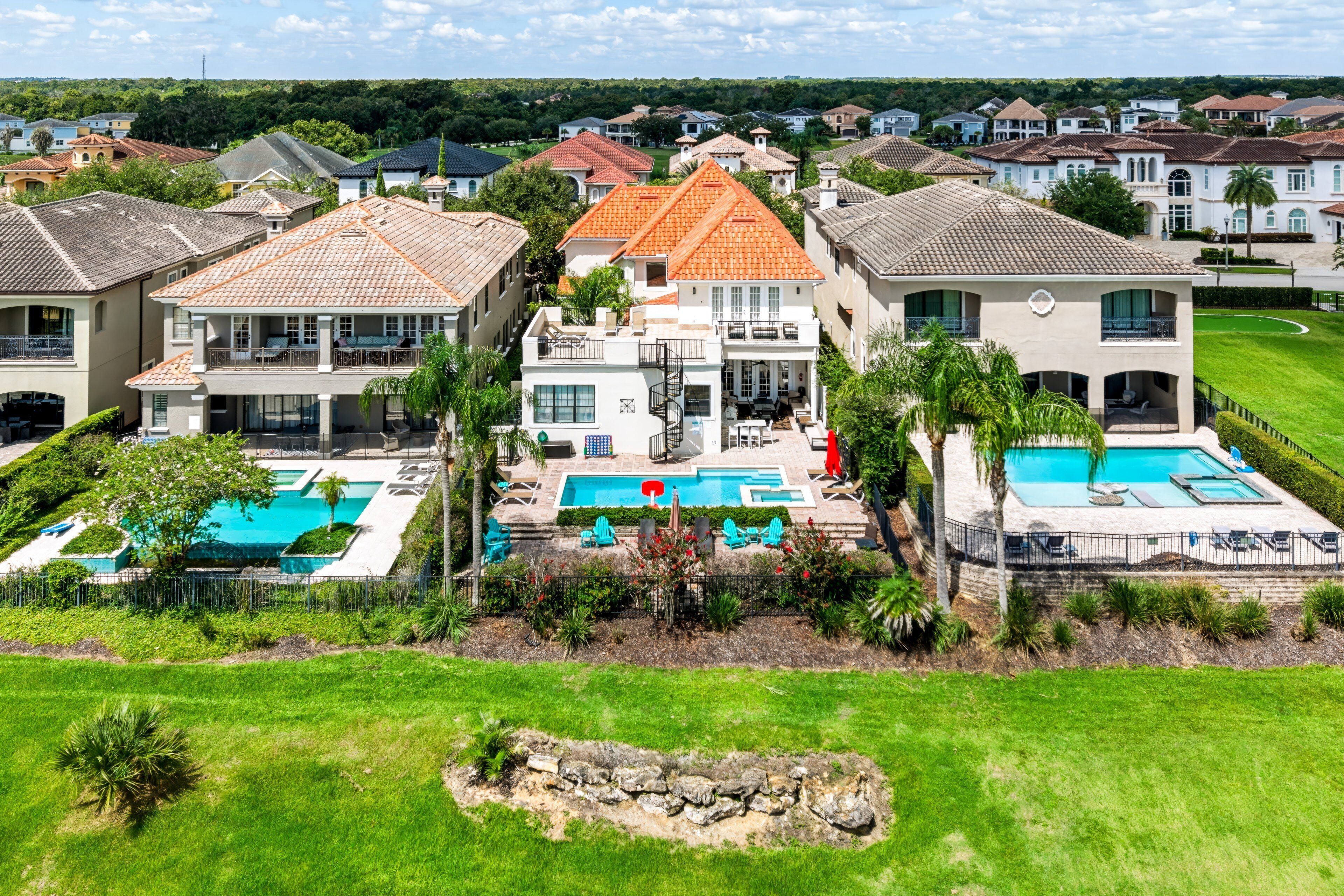 A large residential property with multiple swimming pools, a well-maintained lawn, and a variety of architectural styles.