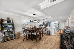 Eine moderne Küche mit Essbereich, Holzboden und einem dekorativen Regal mit Pflanzen.