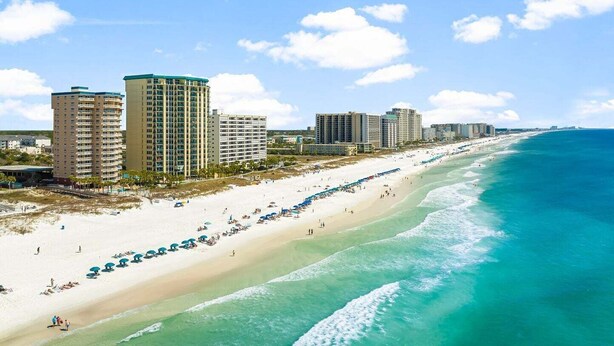 A coastal cityscape with a beachfront hotel, high-rise buildings, and a sandy beach. - ☀️ Destin Dream @ Destin Towers | Gulf Front | 12th Floor | Pool | Beachfront 🌊 (Destin)