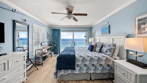 A bedroom with a bed, a desk, a television, a ceiling fan, and a view of the ocean. - ☀️ Destin Dream @ Destin Towers | Gulf Front | 12th Floor | Pool | Beachfront 🌊 (Destin)