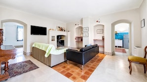 A spacious living area with a sofa, a television, and a fireplace.