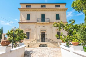 A building with the sign 'VILLA NELLA' at the entrance, a stone-paved courtyard, and potted plants around. - Nella Apartment With Pool, Sannicandro di Bari, Italy (Sannicandro di Bari)