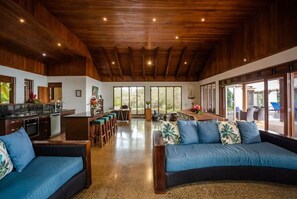 A spacious living area with a wooden ceiling, a kitchen, and a seating area with a sofa and chairs. - Kula Kai Fiji Oceanfront Villa! Sleeps 15 (Fiji)