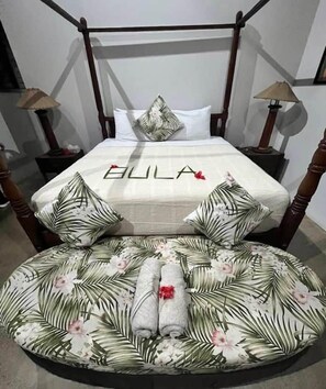 A bed with a canopy, a floral-patterned pillow, and a towel on a round mat. - Kula Kai Fiji Oceanfront Villa! Sleeps 15 (Fiji)