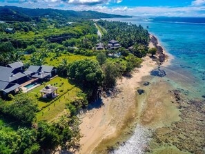 Ein Küstenanwesen mit Strand, Swimmingpool und üppiger Grünlandschaft.