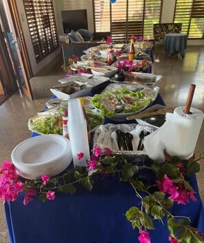 A buffet table with various food items and condiments, set in a room with a view of the outdoors. - Kula Kai Fiji Oceanfront Villa! Sleeps 15 (Fiji)