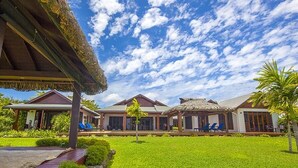 Een resort met meerdere villa's, elk voorzien van een rieten dak en omgeven door weelderige begroeiing.