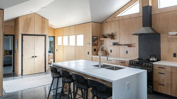 A modern kitchen with a central island, bar stools, a stove, and wooden cabinetry. - Downtown Fruita (Fruita)