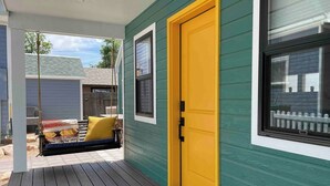 A porch with a yellow door, a bench with a colorful blanket, and a welcome mat. - Downtown Fruita (Fruita)