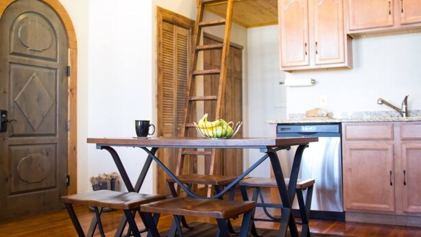 A rustic kitchen with wooden cabinets, a wooden table with benches, and a ladder leaning against the wall. - Studio 508 Downtown Leadville (Leadville)