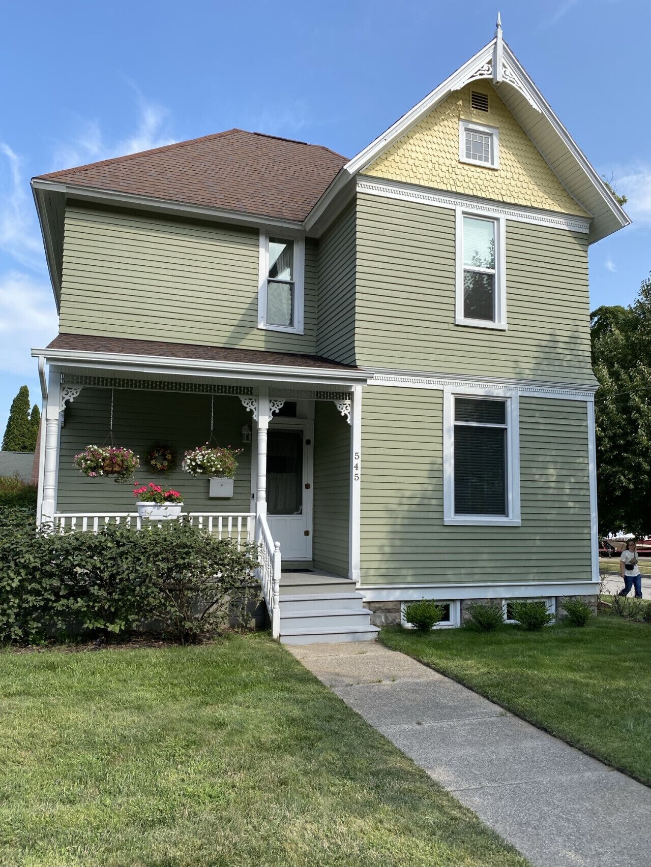 A two-story house with a front porch, a small balcony, and a chimney.