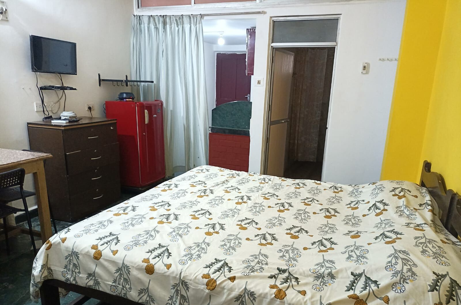Un dormitorio con cama, escritorio, televisor y armario.