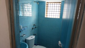 A small bathroom with blue tiles, a toilet, a sink, and a window with bars. - Villa AlexMarie guest house  (Candolim)