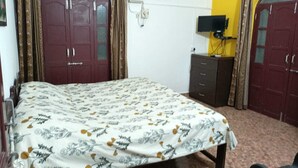 A bedroom with a bed, a wardrobe, a TV on a stand, and an air conditioning unit. - Villa AlexMarie guest house  (Candolim)