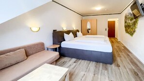 A bedroom with a bed, a sofa, a small table, and a mirror. - Comfortable and versatile room -perfect for relaxation, work and exchange (Winterberg)