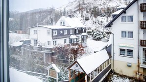 A snow-covered building with a sign reading 'HAUS AM STEIN,' a balcony, and a view of a snowy landscape. - Comfortable and versatile room -perfect for relaxation, work and exchange (Winterberg)