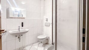 A modern bathroom with a sink, toilet, and shower area. - Comfortable and versatile room -perfect for relaxation, work and exchange (Winterberg)