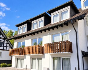 A two-story building with a balcony, large windows, and a sloped roof.
