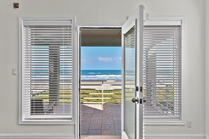 A doorway with white blinds leading to a balcony with a view of the ocean. - Prestigious Private Home with Oceanfront Pool! (South Padre Island)