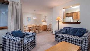 A cozy living room with checkered sofas, a wooden coffee table, and a dining area with a wooden table and chairs. - Kettlebrook Two Bedroom Great Spot for a Skiing Family or Couples (Ludlow)
