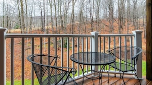 A wooden deck with a white railing, two metal chairs, and a small table. - Kettlebrook Two Bedroom Great Spot for a Skiing Family or Couples (Ludlow)